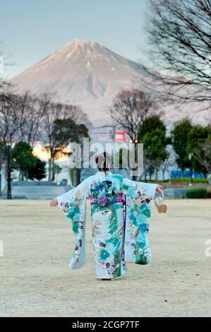 Japanese teenager wearing traditional kimono with arms outstretched contemplating the beauty of Mt. Fuji celebrating the Coming of Age Day. Stock Photo