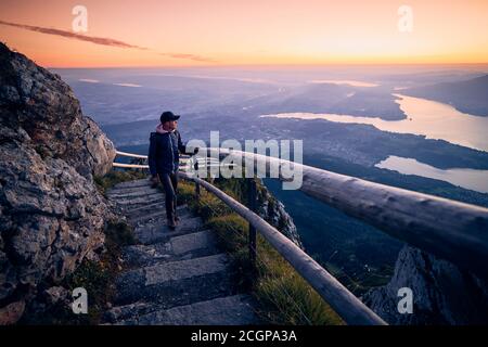 Youg man walking on mountain footpath to Mount Pilatus against Lake Lucerne. Landscape at beautiful sunrise, Switzerland. Stock Photo