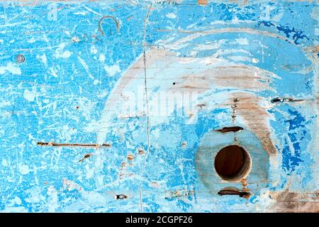 Weathered and scratched blue painted wood with round hole. Stock Photo