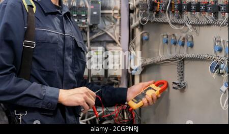 Worker engineer checks electrician measurements with tester multimeter for industrial production Stock Photo