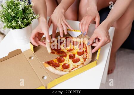 close up of female hands taking pizza slices from cardboard box Stock Photo