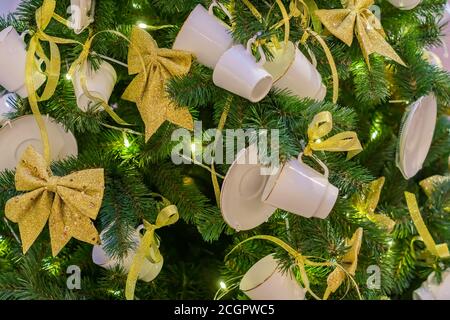 Christmas and New Year holidays background.  Christmas tree decorated with white cups ans sauces. Trendy concept Stock Photo