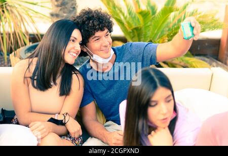 A couple taking selfie with face mask for protection on corona virus time - Young friends having fun with face mask  - New normal lifestyle concept Stock Photo