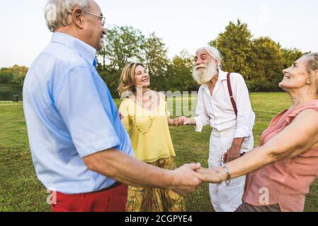 Group of youthful seniors having fun outdoors - Four pensioners bonding outdoors, concepts about lifestyle and elderly Stock Photo