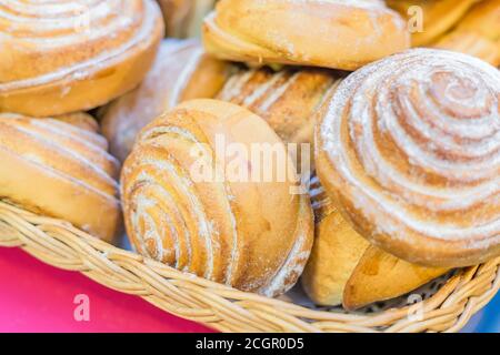 Close up of freshly baked cinnamon rolls buns with powdered sugar in basket Stock Photo
