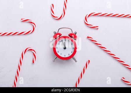 Christmas composition with candy canes and red alarm clock on white background. New Year concept. Top view - Image Stock Photo