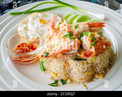 Thai food: Fried rice with large shrimps , a fried egg and a small bowl of nam prik, fish sauce with chili pepper, on a plate. Stock Photo