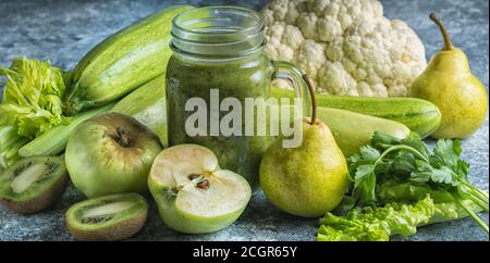 Green healthy smoothie made with green vegetables and fruits on gray concrete background. Healthy food and diet concept. Stock Photo