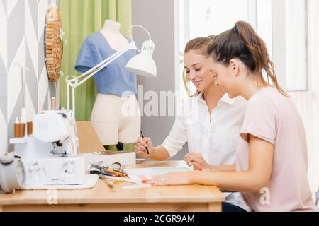 Teacher woman helping students girl sews clothes college, studying fashion and design Stock Photo