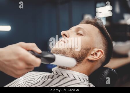Barber removes hair after shaving with face brush, men haircut salon Stock Photo