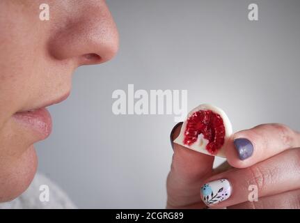 a woman taking and watching before eating a raspberrie dipped in homemade black and white chocolate Stock Photo