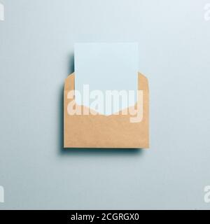 Empty card in kraft envelope on blue background. top view, copy space Stock Photo