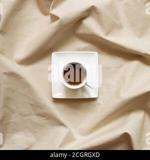 Cup of coffee on brown fabric background. top view Stock Photo