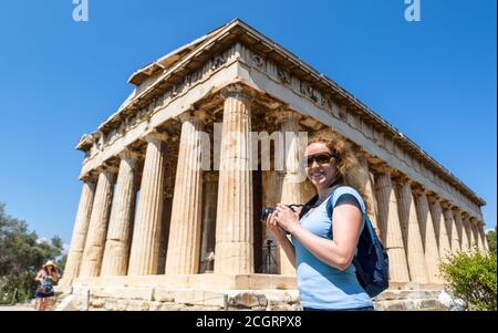 Temple of Hephaestus in Ancient Agora, Athens, Greece. This place is tourist attraction of Athens. Female person photographs the classical Greek build Stock Photo