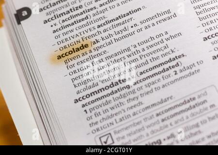 The word or phrase Accolade in a dictionary highlighted with marker ...