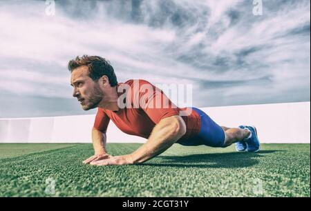 Fit man doing diamond hand push ups exercise at outdoor gym. Core body workout athlete planking or doing pushup on grass Stock Photo