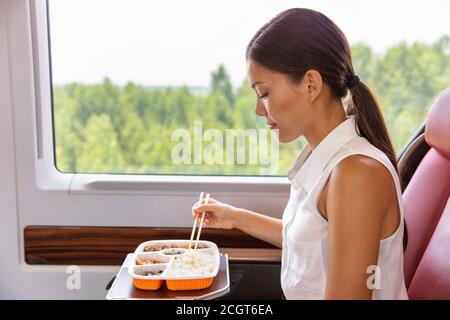 Train commute bus travel Asian business woman eating asian food meal with chopsticks. Businesspeople commuting eating lunch Stock Photo