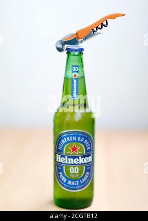Green glass Heineken beer bottle and bottle opener Stock Photo