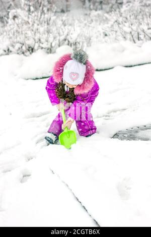 Little kid girl shoveling snow on home drive way Stock Photo