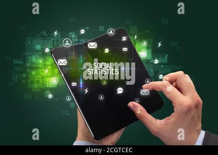 Businessman holding a foldable smartphone with SOCIAL STATISTICS inscription, social networking concept