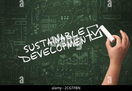 Hand drawing SUSTAINABLE DEVELOPMENT inscription with white chalk on blackboard, new business concept Stock Photo