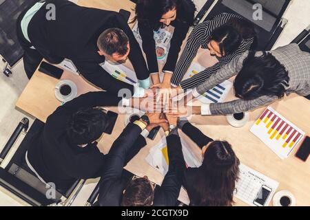 Happy business people celebrate teamwork success together with joy at office table shot from top view . Young businessman and businesswoman workers express cheerful victory showing unity and support . Stock Photo