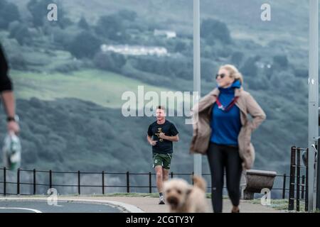Visiting Greystones.  Sea promenade. Walking and exercises. Yong man in Irish colours running at sea promenade. Stock Photo