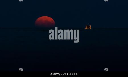 Full Moon rising over the sea near recreational fishing boat. Stock Photo