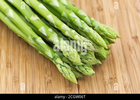 Heap of asparagus sprouts closeup on rustic wooden background, top view Stock Photo