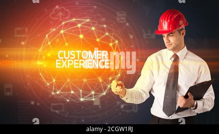 Handsome businessman with helmet drawing CUSTOMER EXPERIENCE inscription, social construction concept Stock Photo