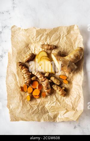 Top view of turmeric roots and ginger on crumpled paper and white surface Stock Photo