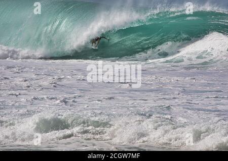 unrecognizable surfer riding inside the curl of a north shore, oahu wave. Stock Photo