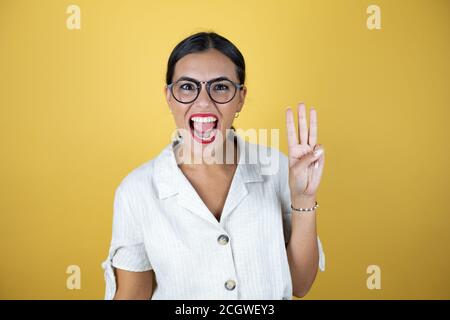 Beautiful woman over yellow background showing and pointing up with fingers number three while smiling confident and happy. Stock Photo