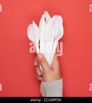 stack of plastic forks and spoons on red background, close up Stock Photo