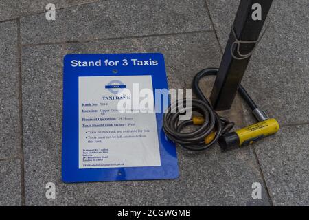 Taxi sign on the pavement next to a broken bike lock. London Stock Photo