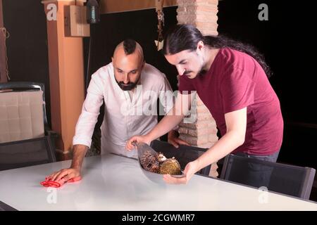 Friendly young men cleaning a table before dinner Stock Photo