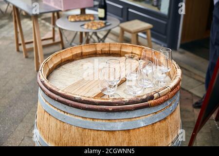 Empty transparent wineglasses standing on an old wooden barrel. Street wine tasting Stock Photo