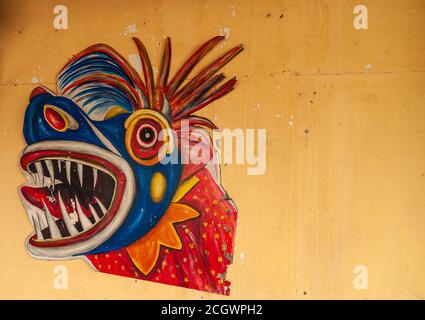 Panama City, Panama - November 30, 2008: Closeup of colorful, mainly blue and red, mask of monster head with sharp teeth, on yellow wall. Stock Photo