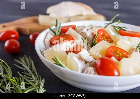 Chicken fillet salad with rosemary, pineapple and cherry tomatoes on dark blue wooden background. close up, copy space. Stock Photo