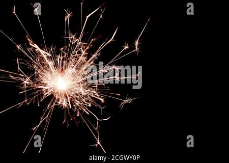 A closeup of a sparkler burning fiercely. Detailed sparks fly in all directions. Black background. Stock Photo