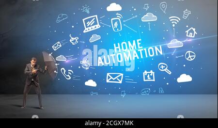 Businessman defending with umbrella from HOME AUTOMATION inscription, modern technology concept Stock Photo