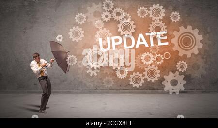Businessman defending with umbrella from UPDATE inscription, technology concept Stock Photo