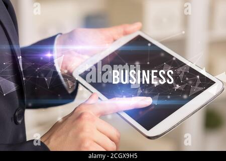 Close up hands using tablet with BUSINESS inscription, modern business technology concept