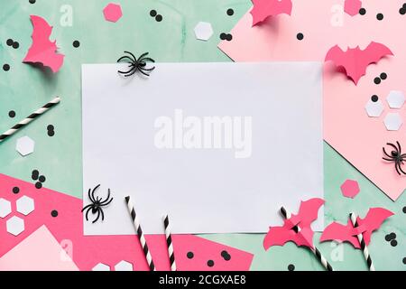 Text space on layered paper background in mint green and pastel pink. Flat lay, Halloween party decor - hexagon confetti, paper drinking straws, flyin Stock Photo