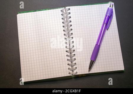 on a black table lies notepad with paper in a cage along with a pen Stock Photo