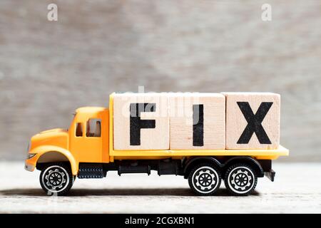 Truck hold letter block in word fix on wood background Stock Photo