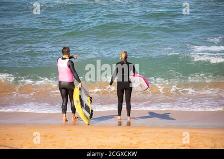 Man and woman wearing wetsuits on the beach with their surfboards, Sydney,Australia Stock Photo