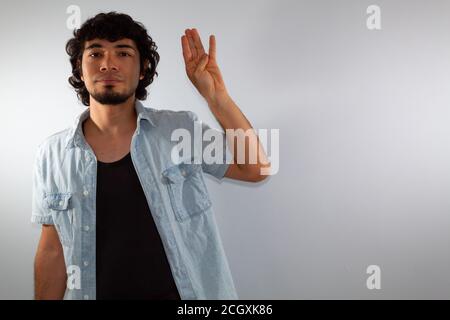 young hispanic deaf man using sign language to communicate, on a white background wearing casual clothes Stock Photo