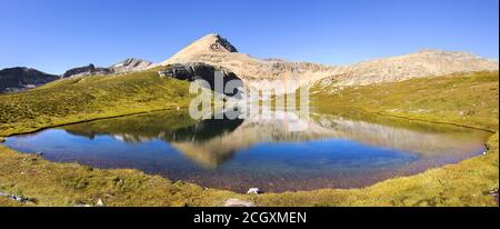 Wide Panoramic Landscape of Scenic Helen Lake and Green Alpine Meadow with Cirque Mountain Peak Reflection in Calm Water. Banff National Park, Canada Stock Photo