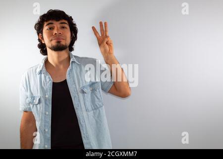 young hispanic deaf man using sign language to communicate, on a white background wearing casual clothes Stock Photo